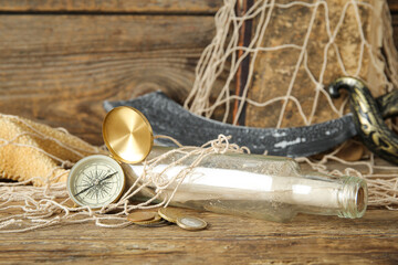 Bottle with scroll, compass, old manuscripts and net on brown wooden background