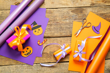 Halloween decorations with gift boxes and wrapping paper on brown wooden background