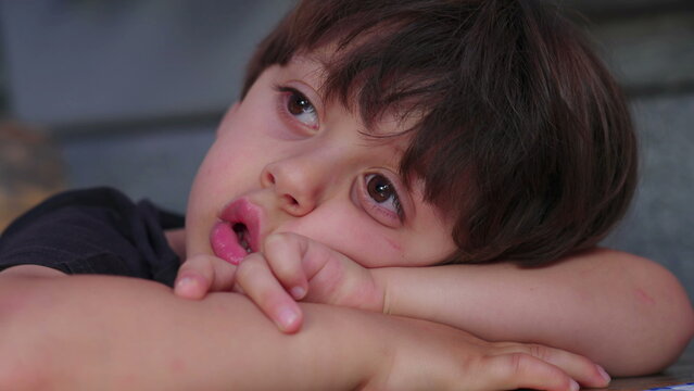 Close-up of bored child drooling and gazing in the distance, daydreamin and lost in thought, close-up face of kid in deep boredom