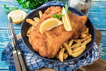 A piece of fried cod with fries on a plate.