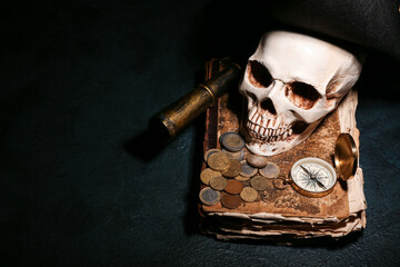 Human skull with old manuscripts, travel equipment, pirate hat and coins on black background