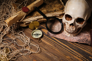 Human skull with old manuscripts, world map and travel equipment on brown wooden background