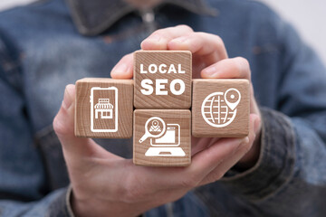 Man holding wooden cubes with icons and inscription: LOCAL SEO. Local search marketing e-commerce....