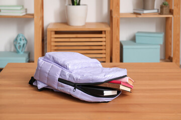 Fototapeta na wymiar Stylish school backpack with books on wooden table in living room