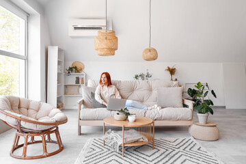 Young woman using laptop on couch in living room