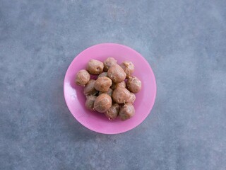 Pile of small raw chicken meatballs or flour mixed with minced chicken and spices and then formed into a round shape on pink plate. Ingredients. bakso