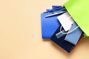 Paper bag with stationery on color background