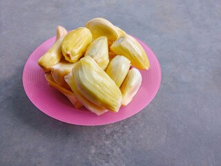 Fresh ripe jackfruit fruit on pink plate over gray background. Yellow sweet fruit. tropical fruit. 