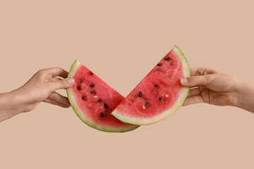 Female hands with slices of ripe watermelon on beige background