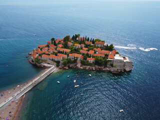Aerial view of Sveti Stefan island and shore in a beautiful summer day, Montenegro from flying drone. Panoramic above view of Saint Stephen luxury resort. Tourism and leisure concept. Aero photography