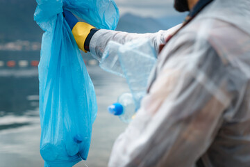 Closeup of unrecognizable person holding plastic bag full of waste collected from beach.