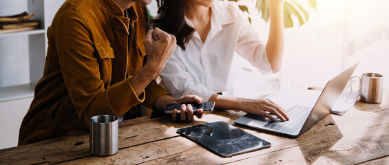 Entrepreneur Asian businessman and businesswoman discussing new business project in tablet in modern Meeting In Modern Office, Asian business casual concept.