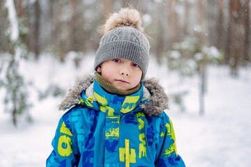 winter portrait of cute caucasian boy on sunny day in forest