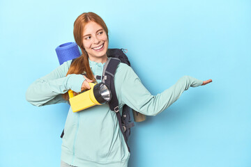 Redhead mountaineer with backpack and flashlight in studio