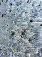 Waves traces on grey sandy beach