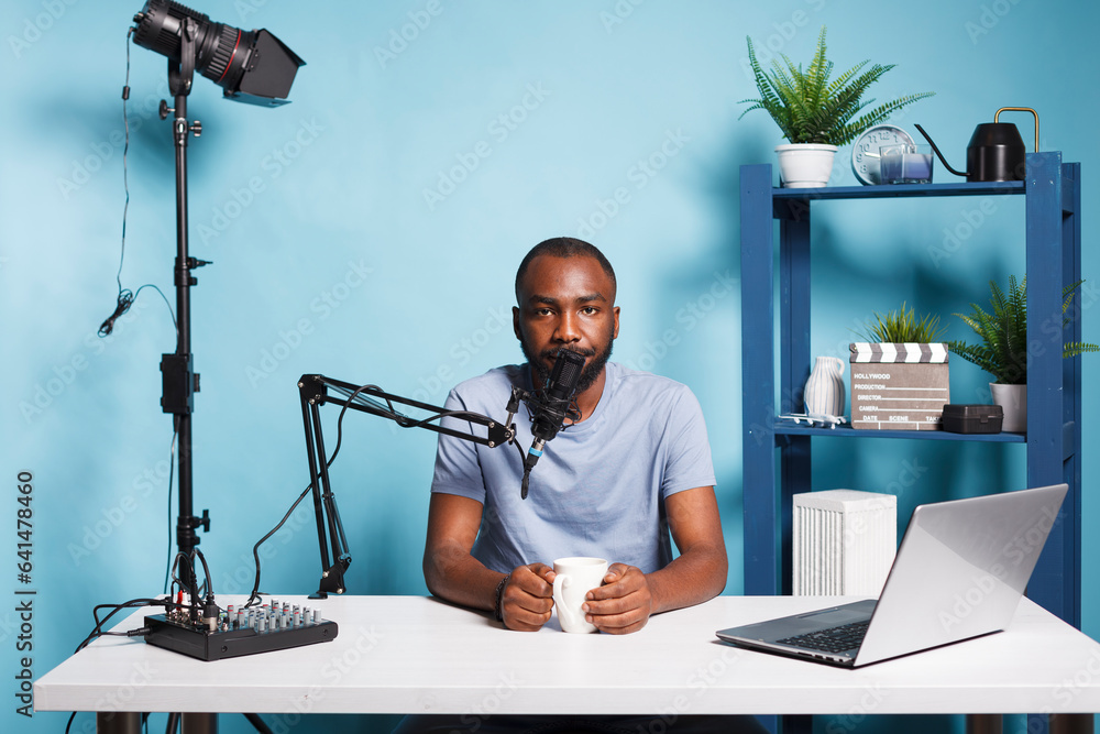 Poster blogger live streaming and broadcasting online for vlog video channel while looking at camera. afric