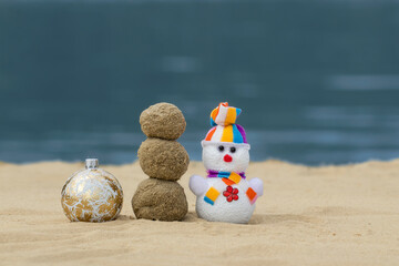 Obraz premium Christmas merry toy and sand snowmen on the beach. New Year vacation discounts in hot countries destinations concept.