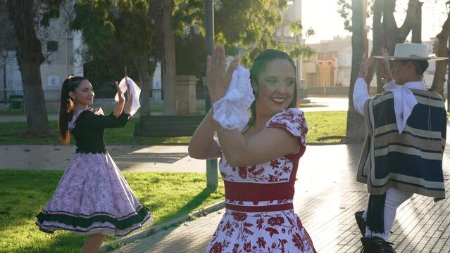 Heterosexual couples dressed in traditional huaso clothes clapping and dancing cueca in the square