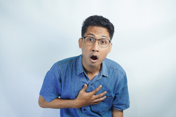 Portrait of young asian man wearing blue shirt shocked to open mouth in front of white background