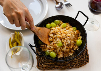 Female waitress hands lay out on plates traditional dish of Aragonese shepherds - migas, decorated...