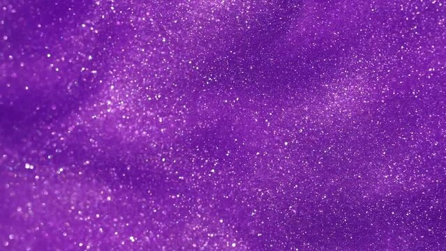 Abstract moving background of silvery particles in purple fluid.Bright Glittering dust particles floating in liquid. Magic dust waves. Slow Motion 4K footage.