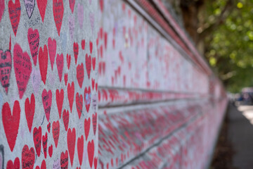 National Covid Memorial Wall overlooking the River Thames in Lambeth, London UK. The red hearts are inscribed with the names of people who died in the Coronavirus pandemic.