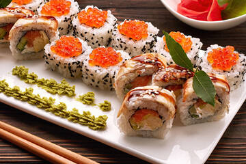 Delicious sushi rolls with wasabi and ginger with chopsticks. Close-up
