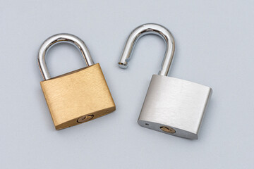 Locked golden and unlocked silver padlock on the gray background.