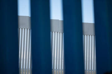 Looking through the slats of the border wall separating the United States and Mexico, with a view of the tall steel structure.