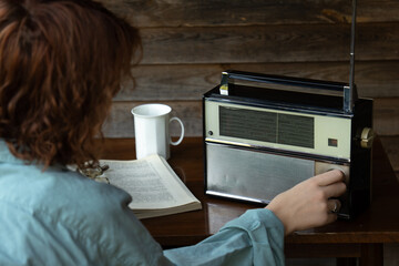 Girl searching for a radio station frequency or wave on a vintage radio receiver.