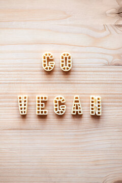 Naklejki Inscription ‘Go vegan’ written with alphabet pasta on wooden table, directly above view 