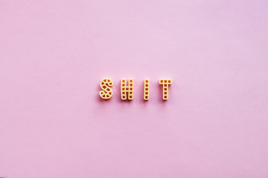 Close-up view of alphabet pasta forming word &lsquo;shit&rsquo; against pink background 