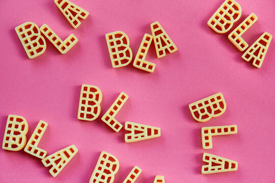 Close-up view of alphabet pasta letters forming words &lsquo;bla&rsquo; against pink background  