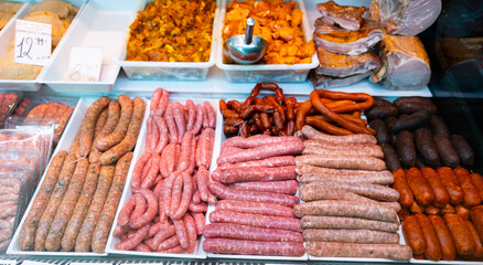Variety of traditional spanish sausages arranged in glass display case of butchery shop. Popular meat products concept