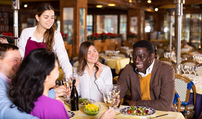 Smiling couple on friendly meeting over dinner with wine in restaurant