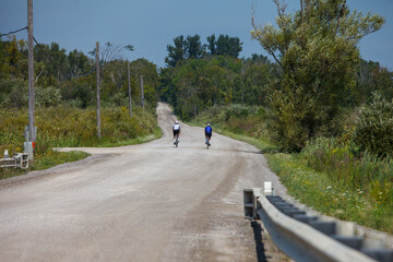 Two cyclists riding on a country road. 