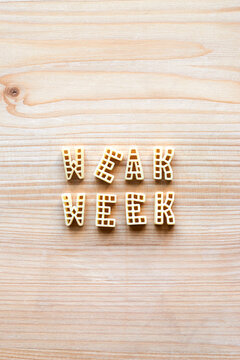 Alphabet pasta forming words &lsquo;week&rsquo; and &lsquo;weak&rsquo; on wooden table background, directly above view 