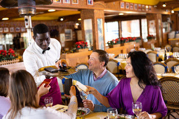 African American waiter brought mobile phones on the tray of the restaurant