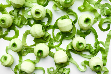 Directly above view of peeled juicy apples and its green peel lying on white table background