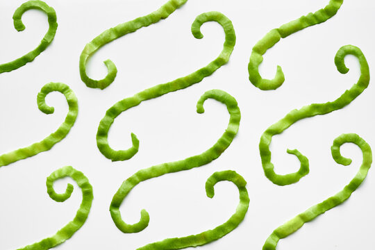Close-up view of green apple peel strips with curls isolated on white background 