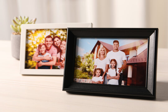 Frames with family photos on white wooden table indoors