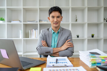 Obraz premium Asian man in corporate office, businessman who owns a startup company sits in office, professional executive runs a company, managing the business to grow and make a profit. Company executives' ideas.