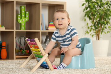Little child with abacus sitting on plastic baby potty indoors