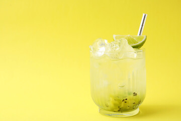 Glass of refreshing drink with kiwi and lime on yellow background, space for text