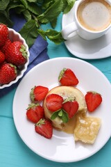 Tasty vanilla fondant with white chocolate, strawberries and cup of coffee on light blue wooden table, flat lay