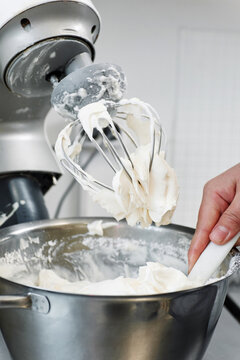 Close-up view of unrecognizable cook making whipped cream with modern mixer in confectionery kitchen 