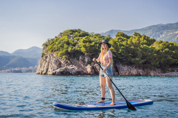 Young women Having Fun Stand Up Paddling in blue water sea near st stefan island against the...