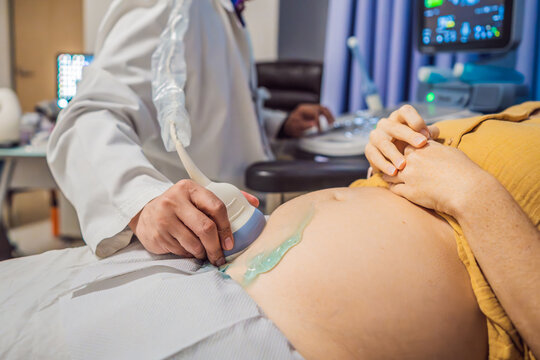 In the Hospital, Close-up Shot of the Doctor does Ultrasound Sonogram Procedure to a Pregnant Woman. Obstetrician Moving Transducer on the Belly of the Future Mother