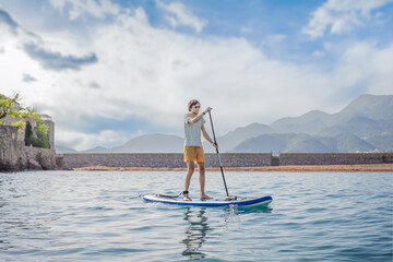 Young men Having Fun Stand Up Paddling in blue water sea near st stefan island in Montenegro. SUP