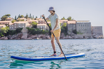 Young men Having Fun Stand Up Paddling in blue water sea near st stefan island in Montenegro. SUP